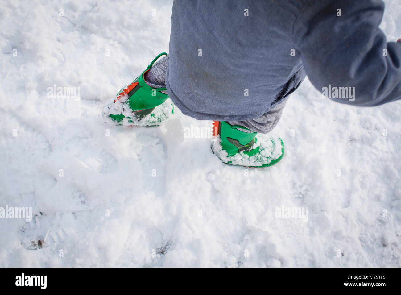 I ragazzi verde wellies dinosauro a piedi attraverso la neve fresca Foto Stock