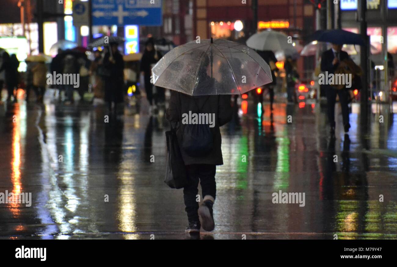 Freddo umido wintery pedoni con ombrelloni su un wet notte piovosa a Tokyo Foto Stock