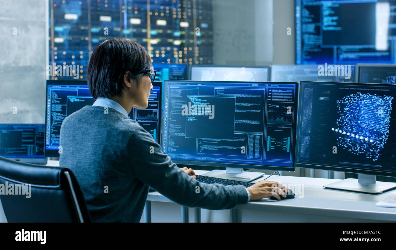 Nel sistema della sala di controllo operatore tecnico lavora presso la propria workstation con più display che mostra la grafica. Tecnico IT lavora sulla ricerca di intelligenza artificiale Foto Stock