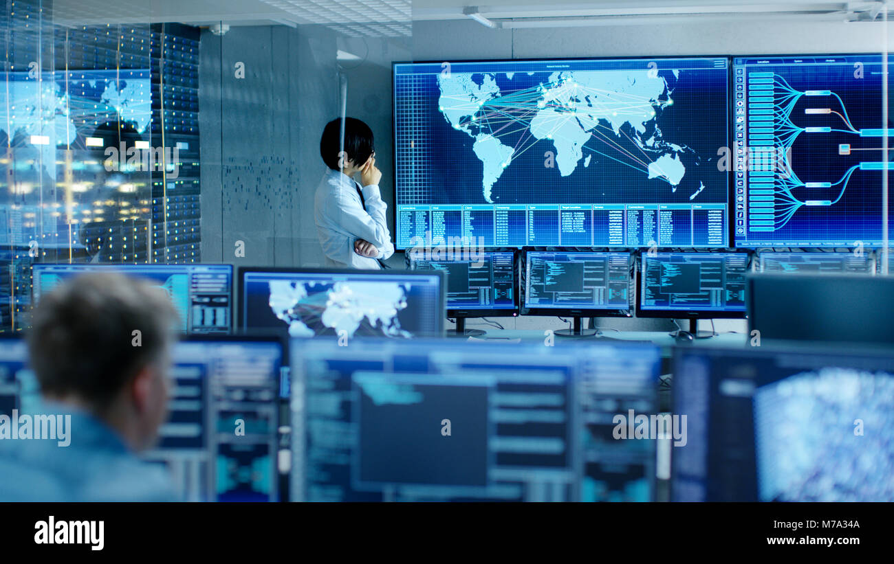Nel sistema camera di controllo Chief Engineer pensa mentre davanti al grande schermo con la mappa interattiva su di esso. Il centro dati è piena di Monitor Foto Stock