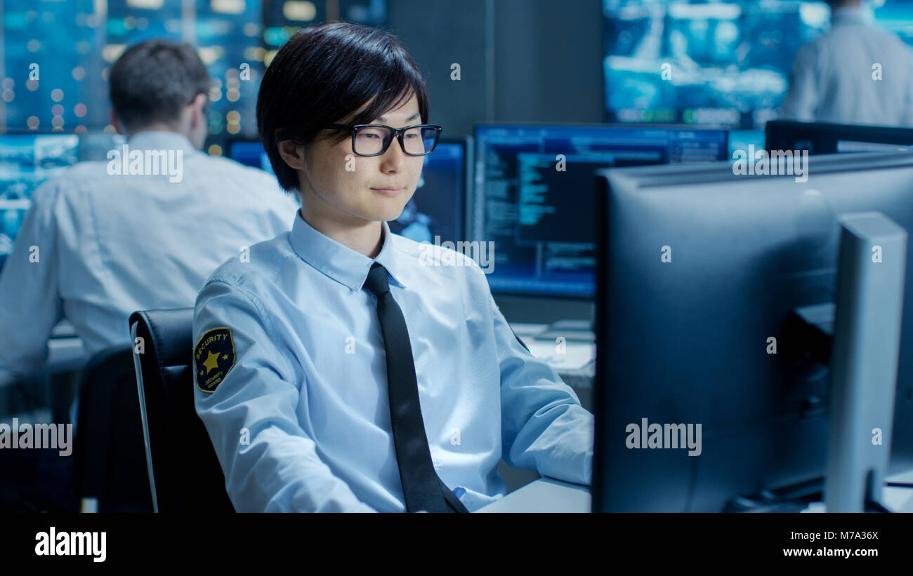 In Security Command Center Officer presso la sua workstation i monitor di schermi multipli per infiltrazione illegale. Essi stanno a guardia Persona importante. Foto Stock