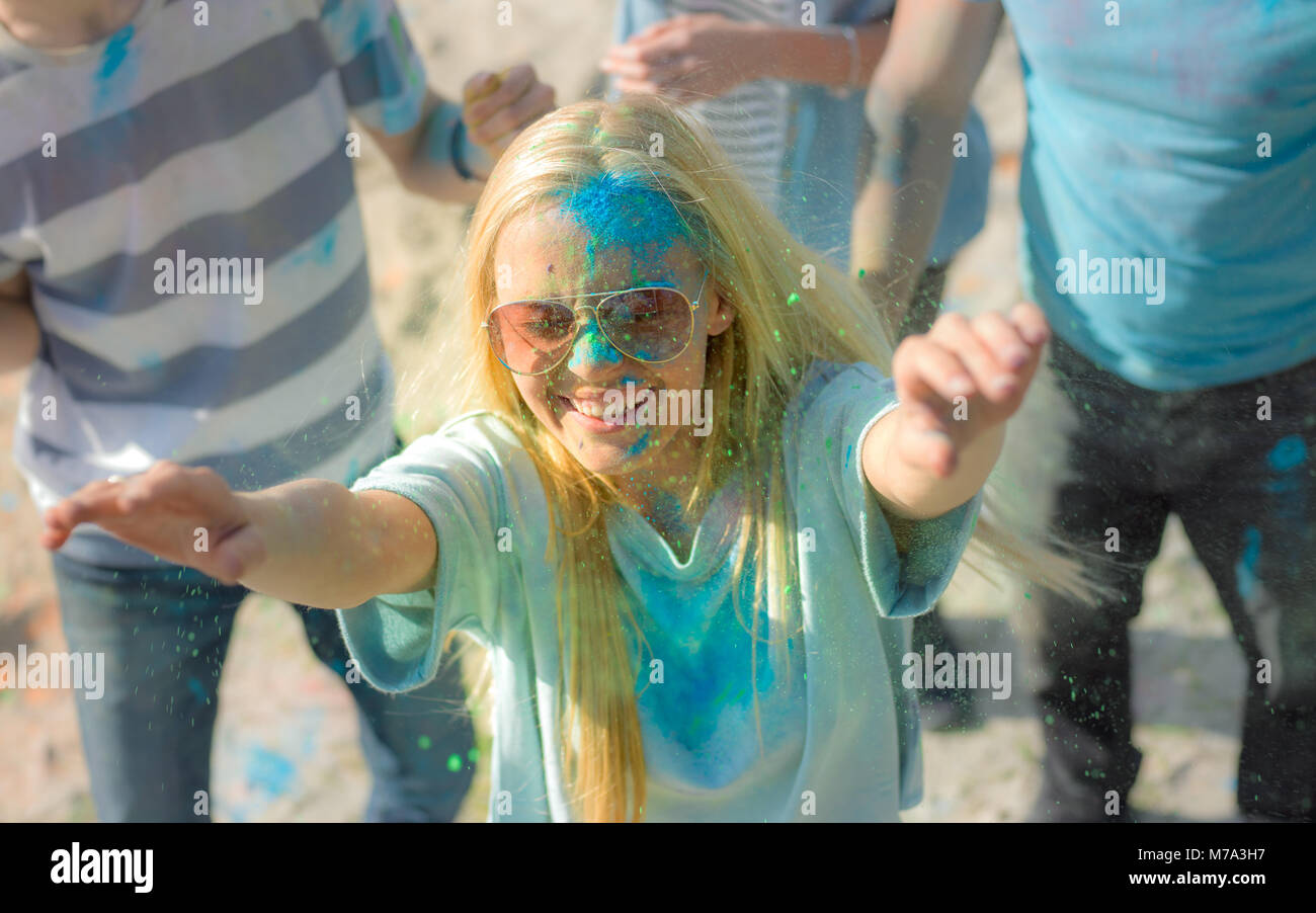 Alta angolazione della ragazza bionda gettare polvere colorata in mezzo alla folla in mezzo Hindu Holi festival celebrazioni. Essi hanno un enorme divertimento in questa giornata di sole Foto Stock