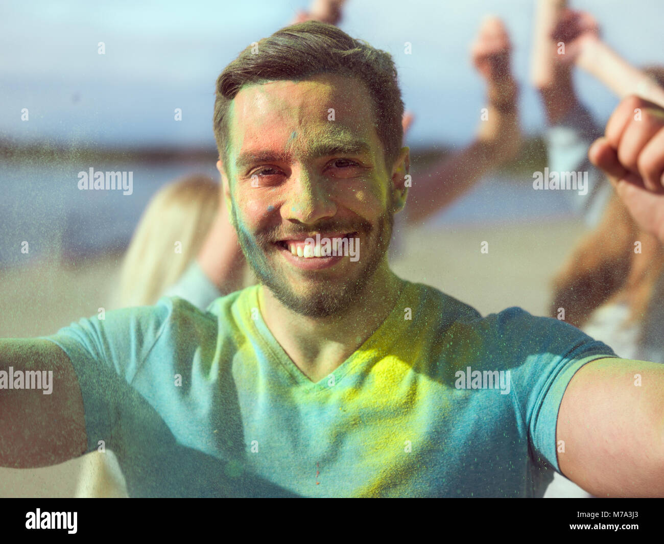 Selfie Ritratto di un uomo muscoloso celebrando di Holi festival con i suoi amici. Il suo viso e vestiti sono ricoperti di polvere colorata. Foto Stock