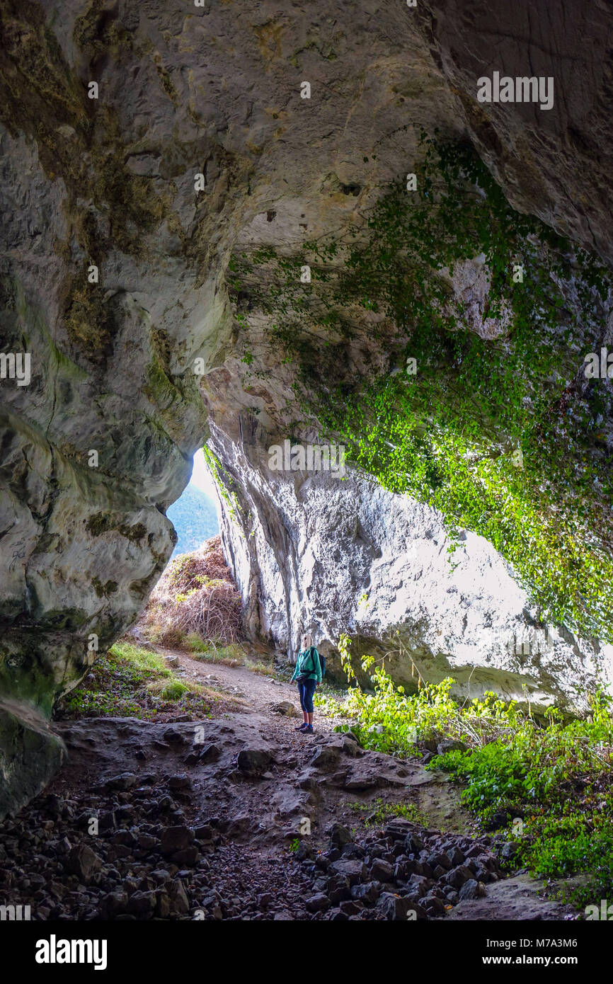 Figura femminile nella grotta di edera con il sole che splende in, Niaux, Pirenei, Francia Foto Stock