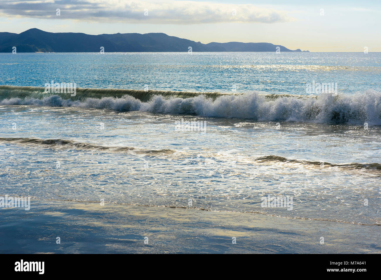Le onde che si infrangono a spiriti Bay (Piwhane) con Cape Reinga a distanza, Isola del nord, Nuova Zelanda Foto Stock