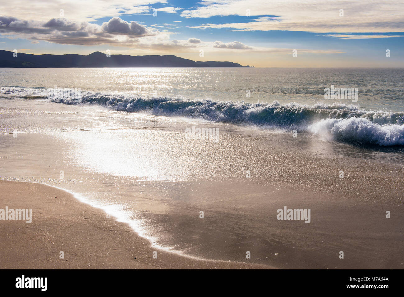 Le onde che si infrangono a spiriti Bay (Piwhane) con Cape Reinga a distanza, Isola del nord, Nuova Zelanda Foto Stock