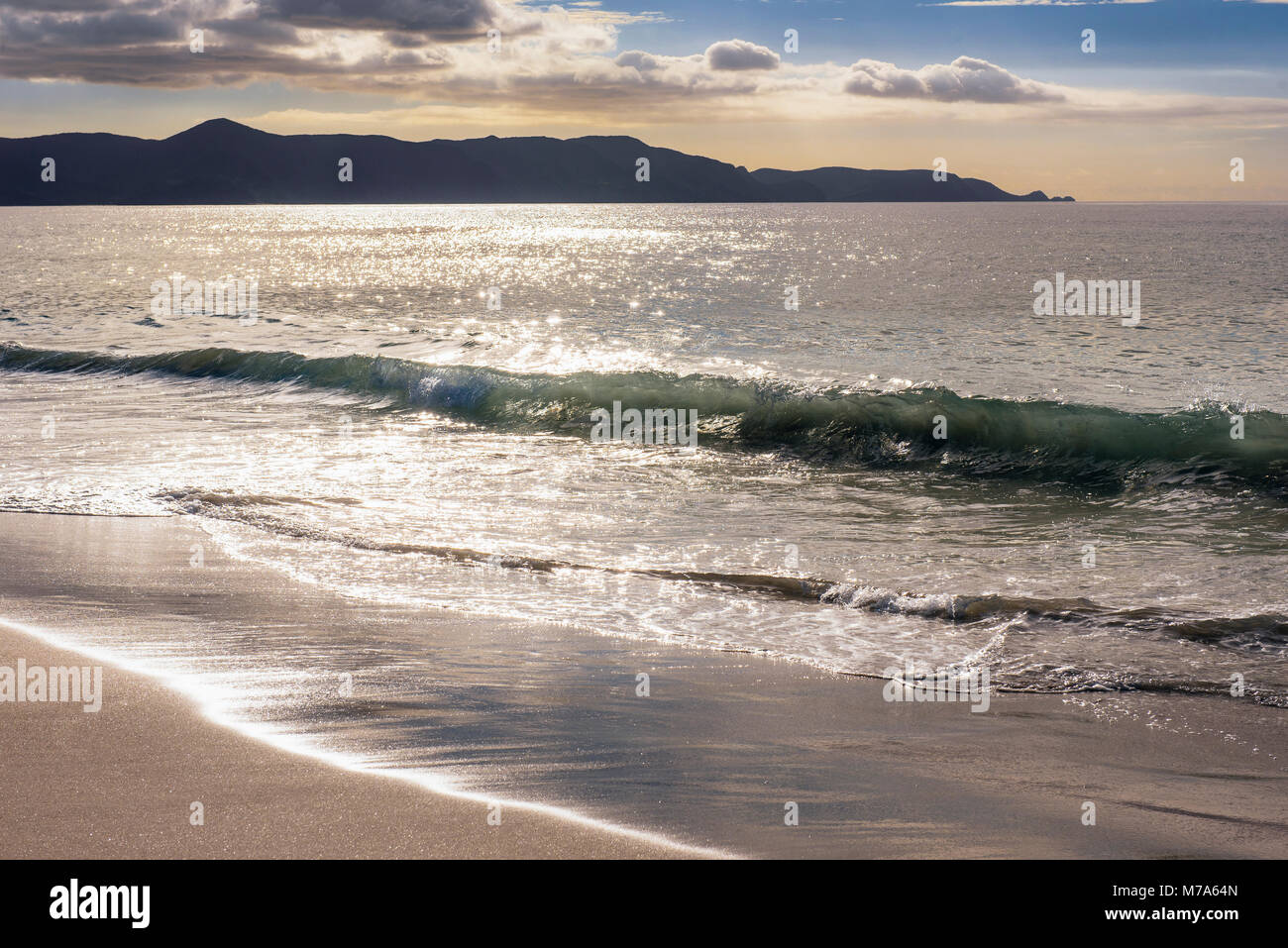 Le onde che si infrangono a spiriti Bay (Piwhane) con Cape Reinga a distanza, Isola del nord, Nuova Zelanda Foto Stock