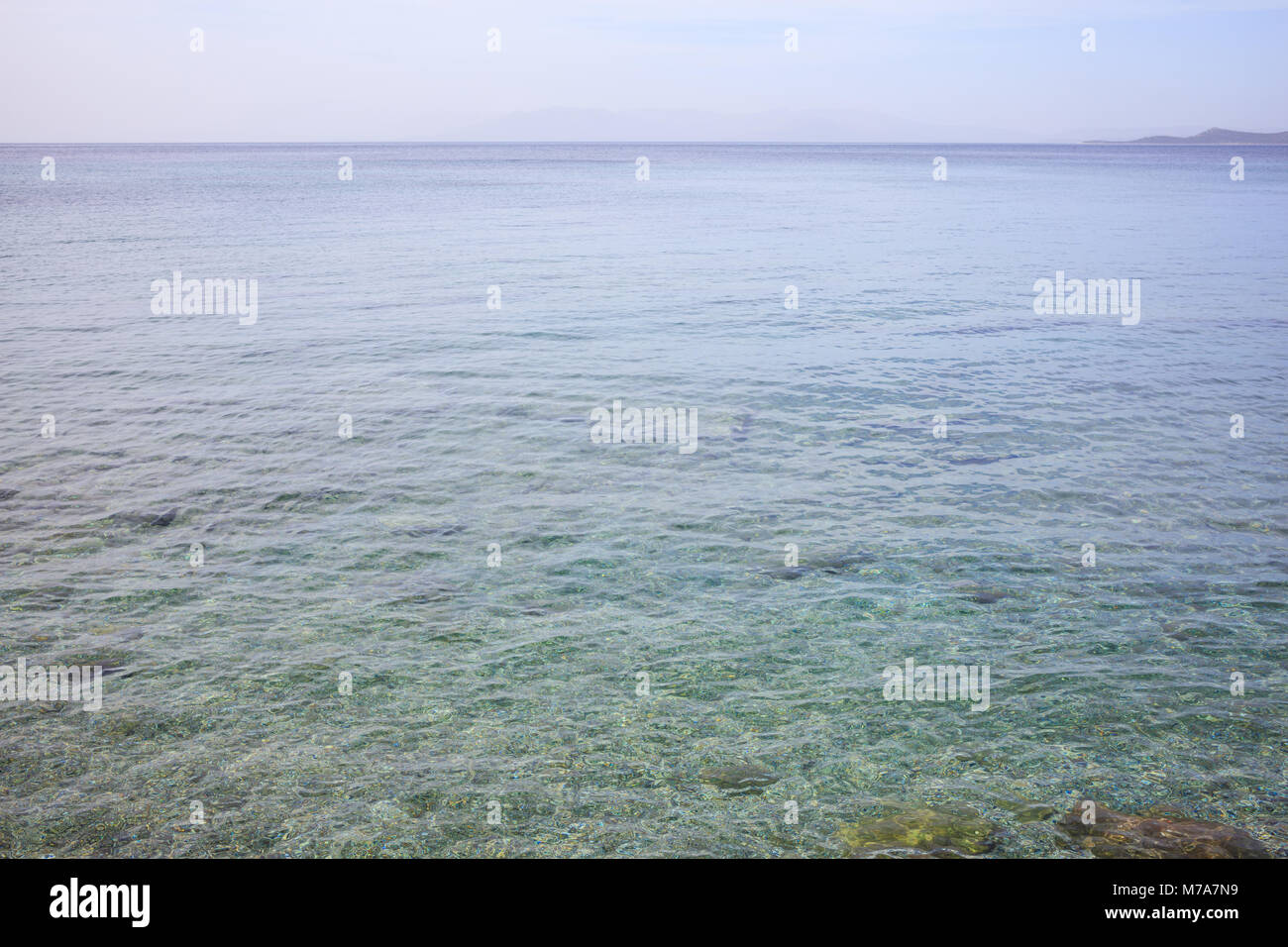 Trasparente la superficie del mare. Fondale basso, cielo blu sullo sfondo Foto Stock
