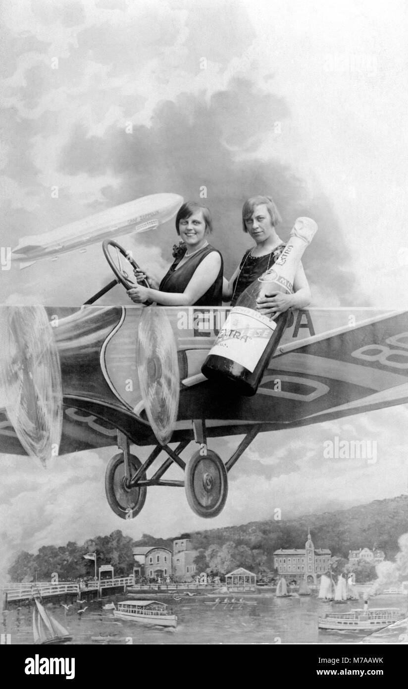 Due donne con una bottiglia di vino frizzante in un aeromobile mock-up, Capodanno, 1920s, Germania Foto Stock