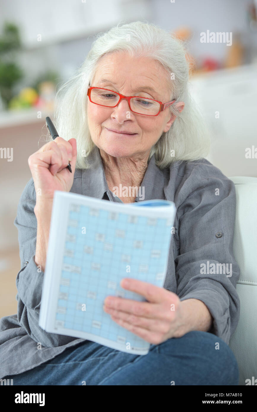 Signora anziana sconcertante su una rivista quiz Foto Stock