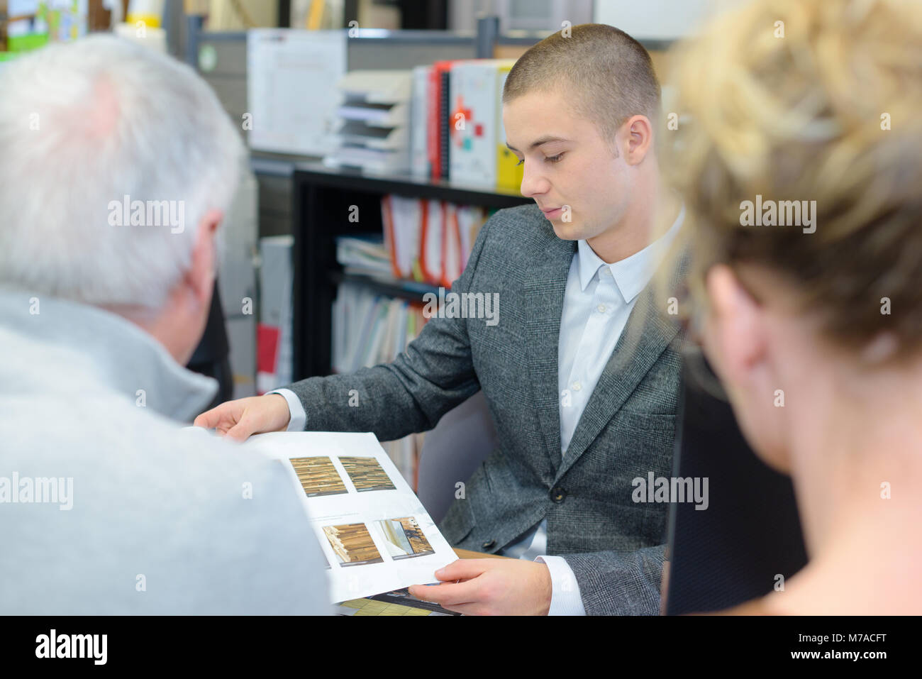 Venditore che mostra ai clienti il parquet in legno campioni brochure Foto Stock