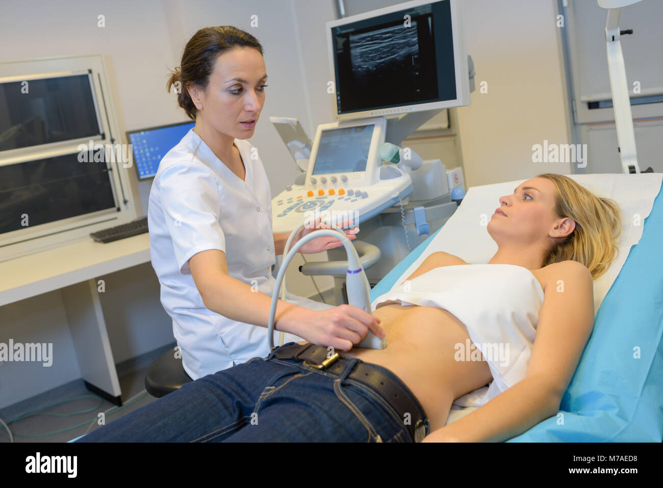 Giovani donne medico lo spostamento del trasduttore a ultrasuoni sul ventre womans Foto Stock