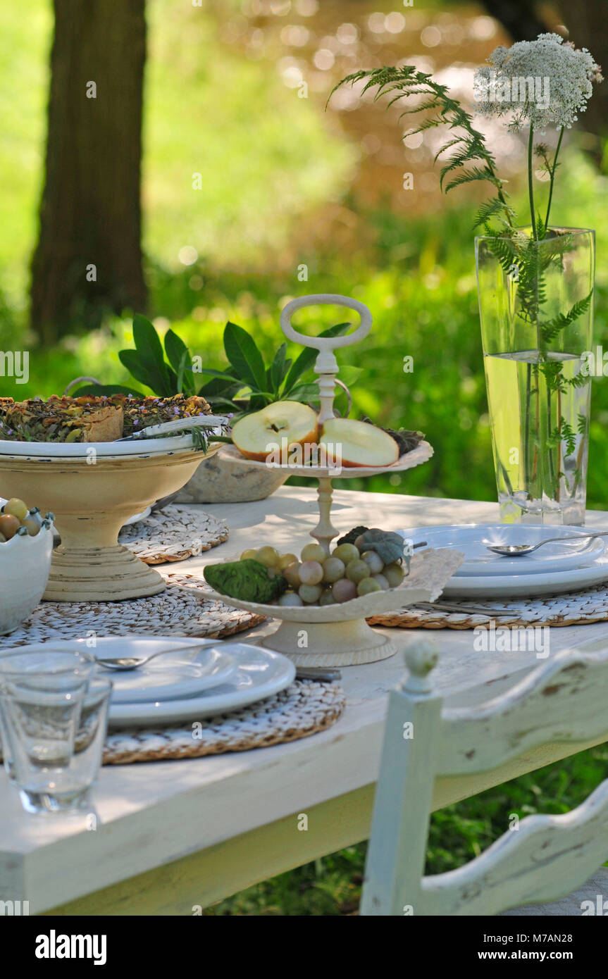 Mangold quiche e Etagere con spicchi di mela su bianco tavola apparecchiata, sullo sfondo sfocato prato e brook Foto Stock