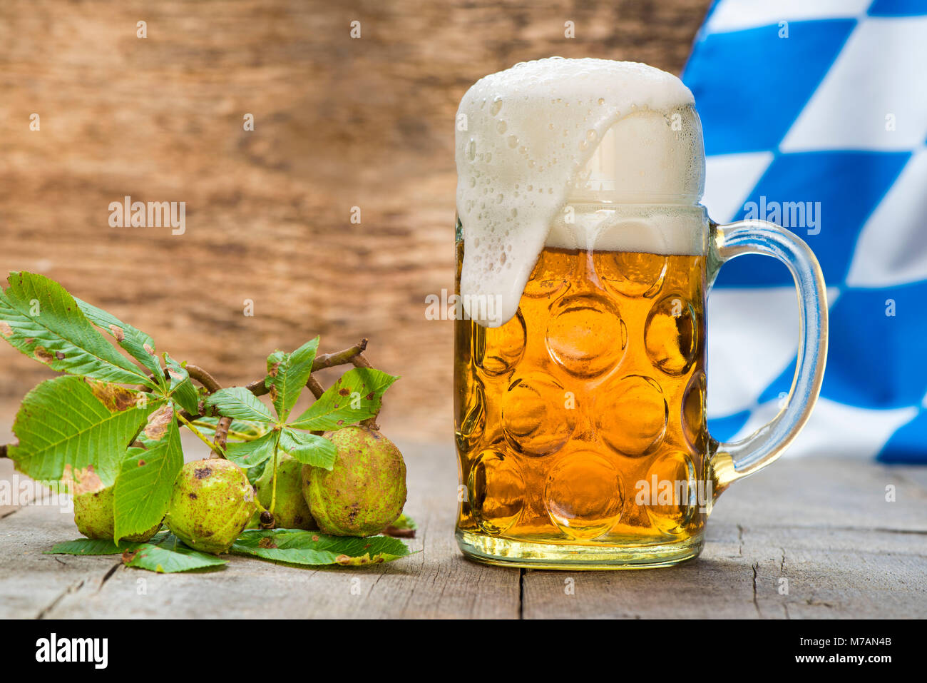 Boccale di birra con la birra in Baviera con castagne e bandiera bavarese in bianco-blu Foto Stock