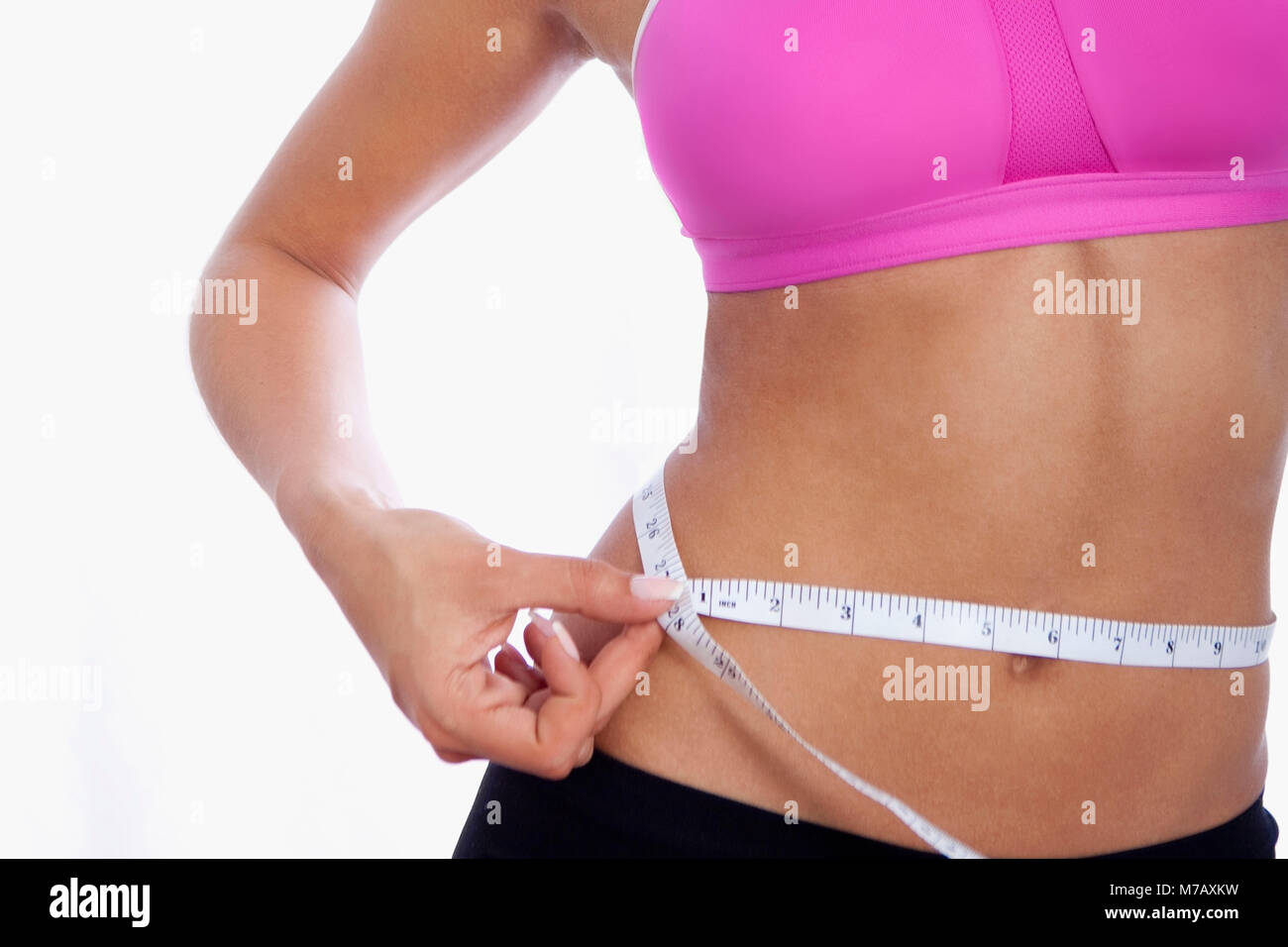 Metà vista in sezione di una donna misurando il suo girovita con un nastro di misurazione Foto Stock