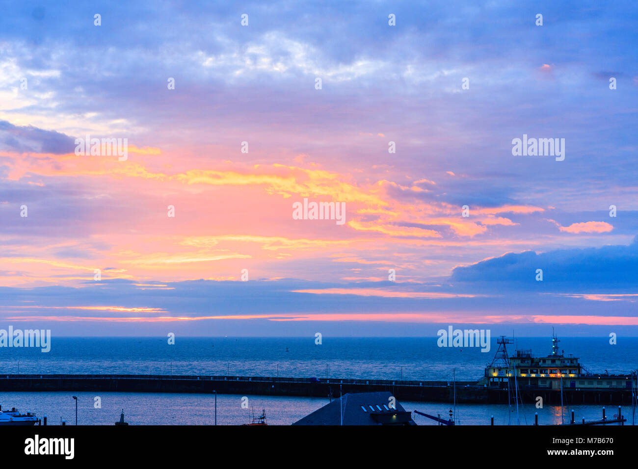 Inghilterra, Ramsgate porto. Alba sul canale Inglese. Nuvole e cielo blu con evidenza di colore brillante durante l'alba e tramonto, sun non effettivamente visto, dietro il cloud. Foto Stock