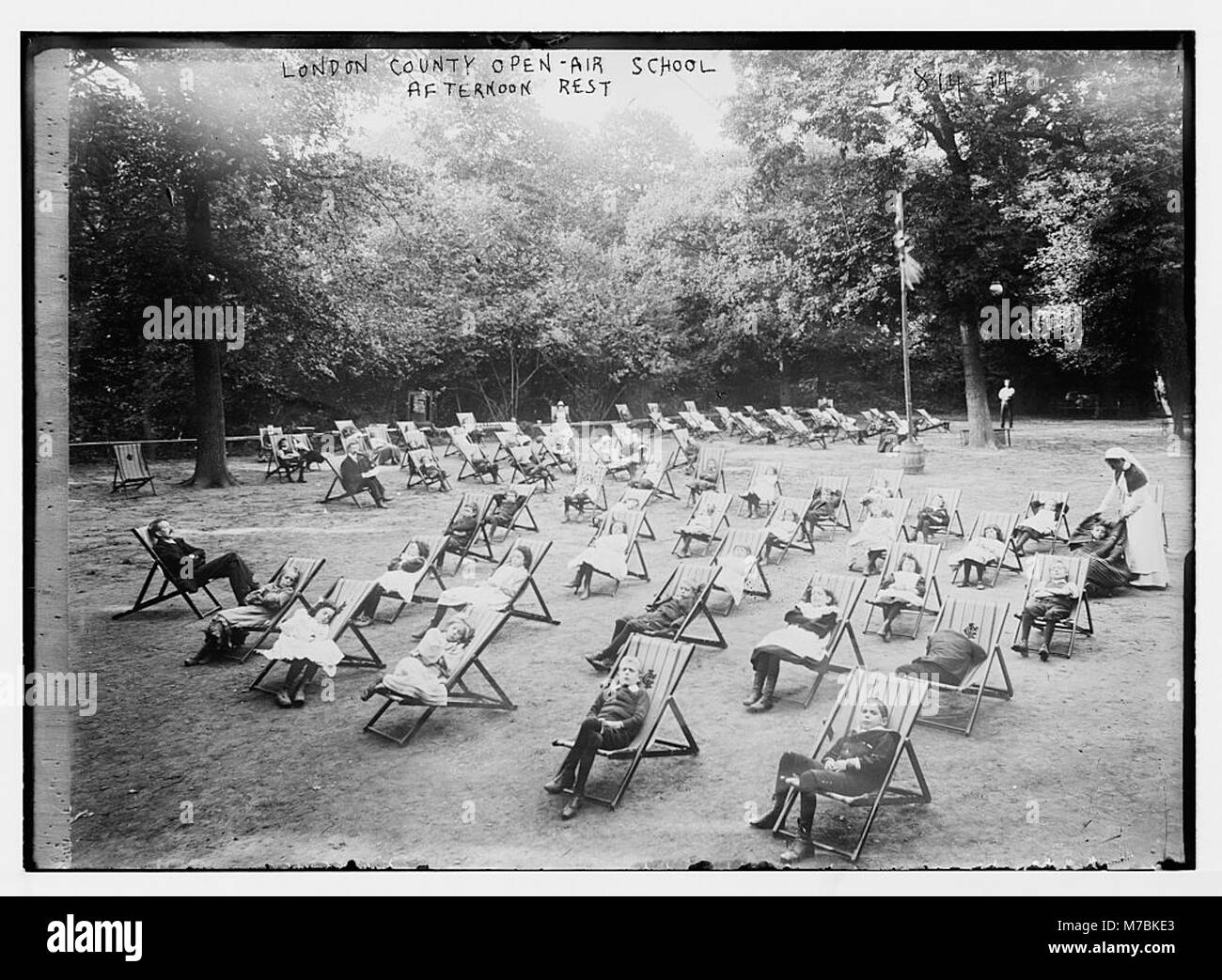 Questa immagine mostra i bambini che riposano sulle sedie nel pomeriggio alla London County Open-air School, sottolineando l'approccio unico della scuola all'educazione all'aperto e la sua attenzione al benessere degli studenti in un ambiente naturale. Foto Stock