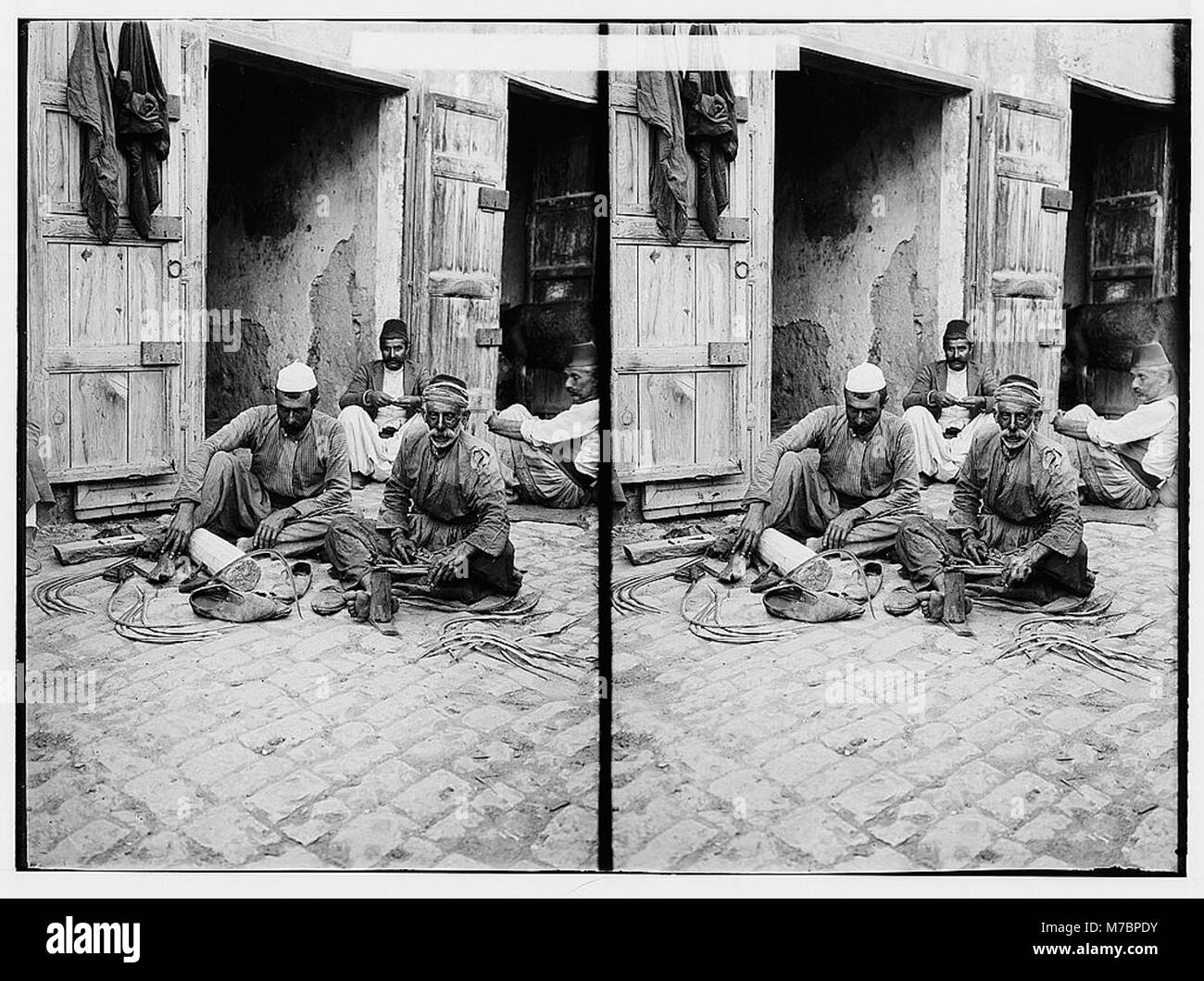 Una scena di individui che affilano falchi, probabilmente in preparazione al lavoro agricolo. Questa attività è stata fondamentale per la manutenzione degli attrezzi agricoli durante le stagioni di raccolta. Foto Stock
