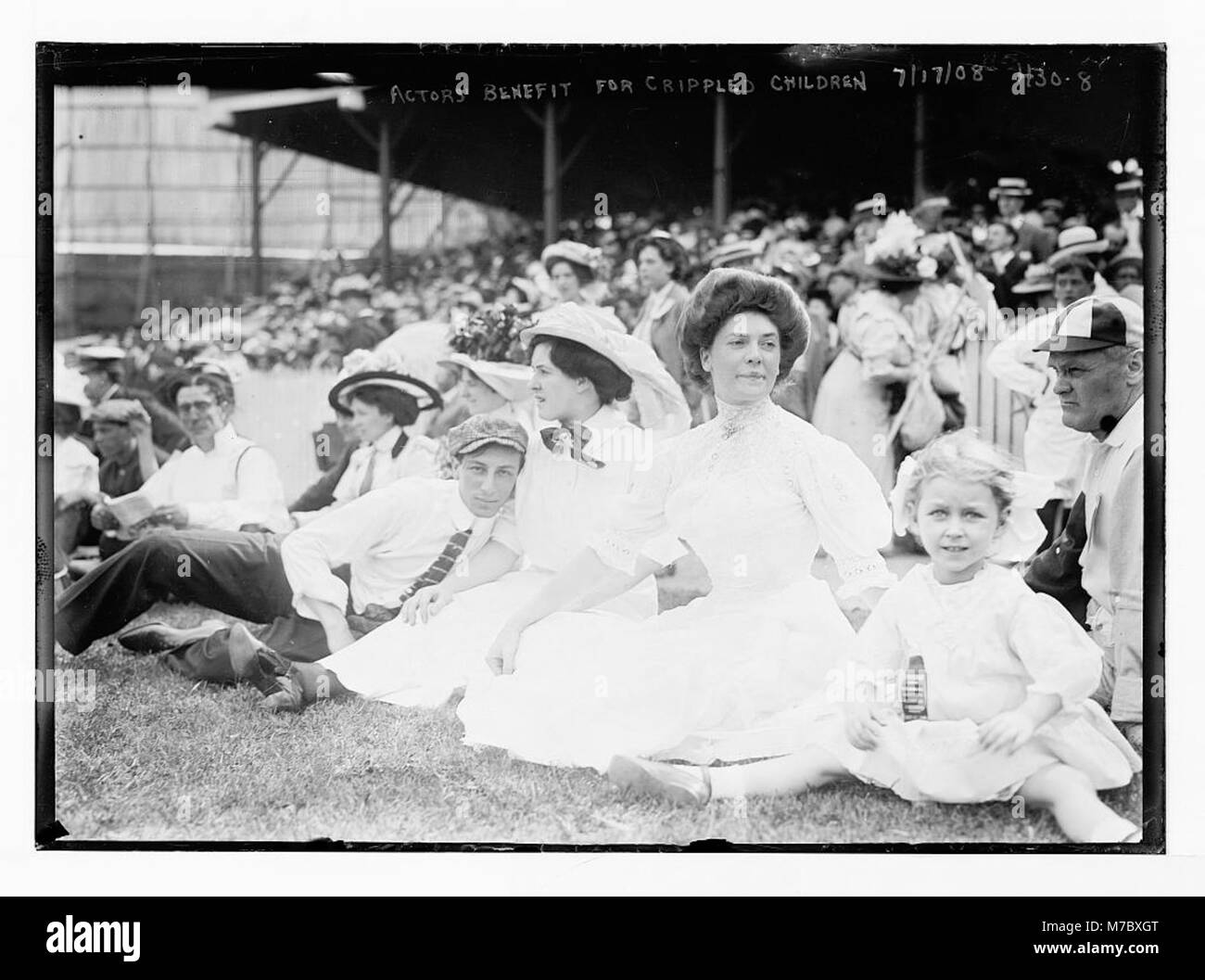 Una fotografia di attori seduti a terra durante un evento di beneficenza per bambini paralizzati, che riflette gli sforzi caritatevoli della comunità di intrattenimento durante i primi anni del XX secolo. Foto Stock
