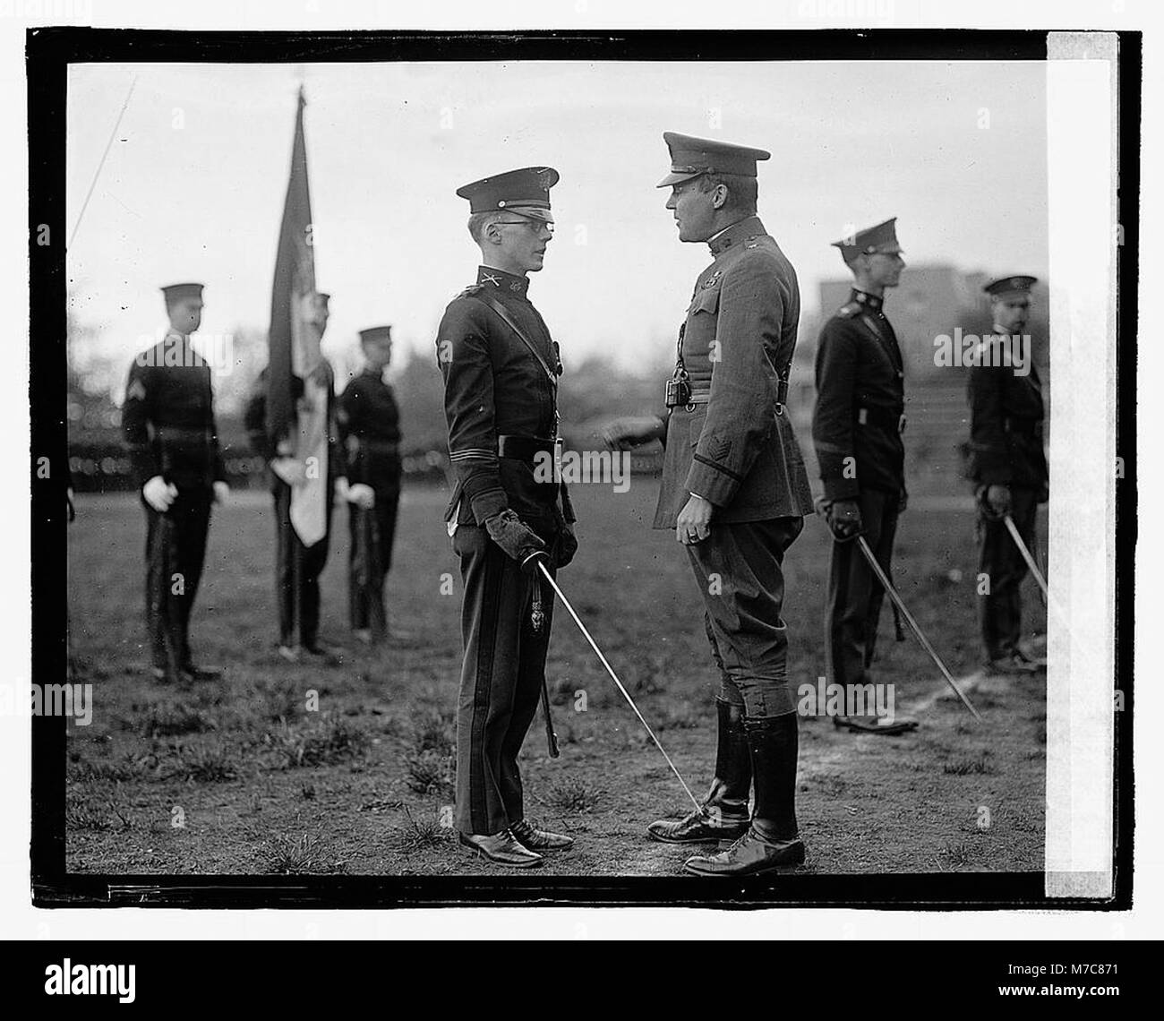 Questa fotografia mostra un gruppo di uomini non identificati in uniforme che prendono parte a una cerimonia, probabilmente di natura militare o ufficiale. Foto Stock
