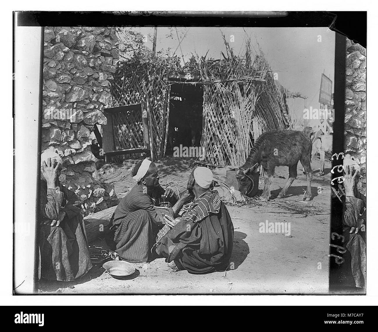 Questa immagine cattura un barbiere di strada egiziano che esegue il suo mestiere, probabilmente in un vivace ambiente urbano, che riflette la tradizionale cultura del barbiere in Egitto. Foto Stock