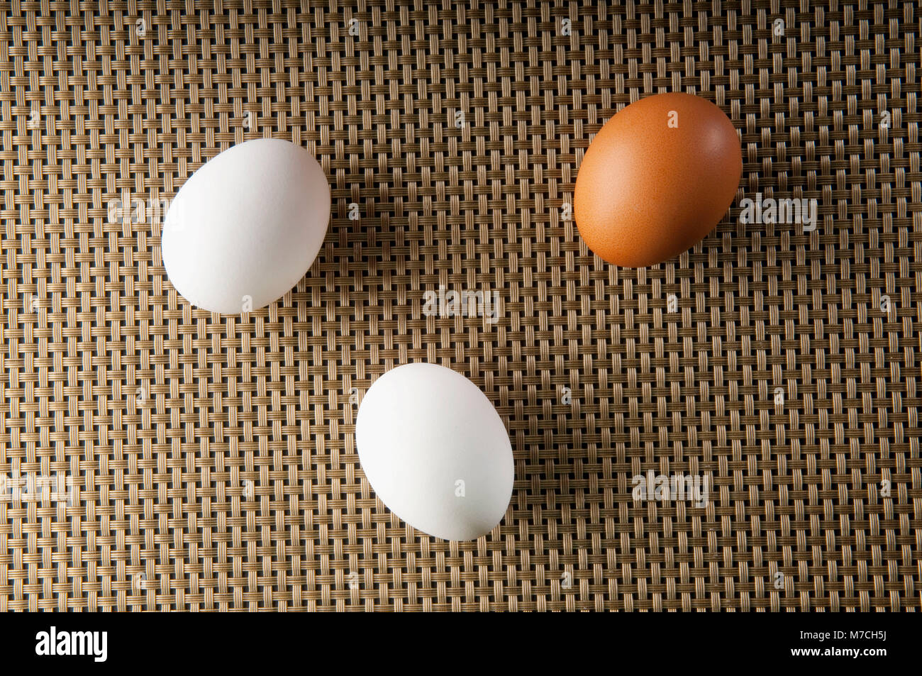 Close-up di un uovo di colore marrone con due uova di colore bianco Foto Stock
