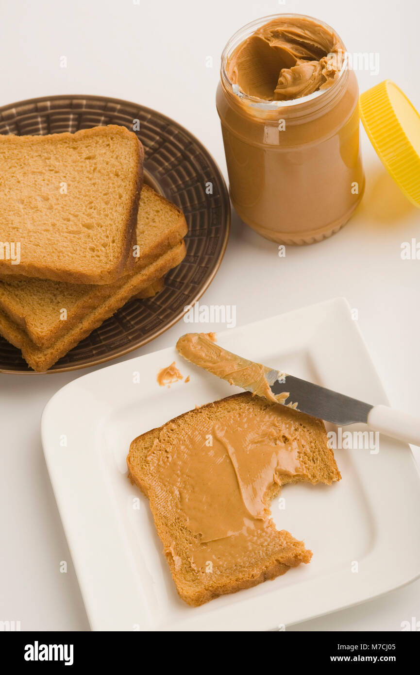 Burro di arachidi jar con le fette di pane Foto Stock