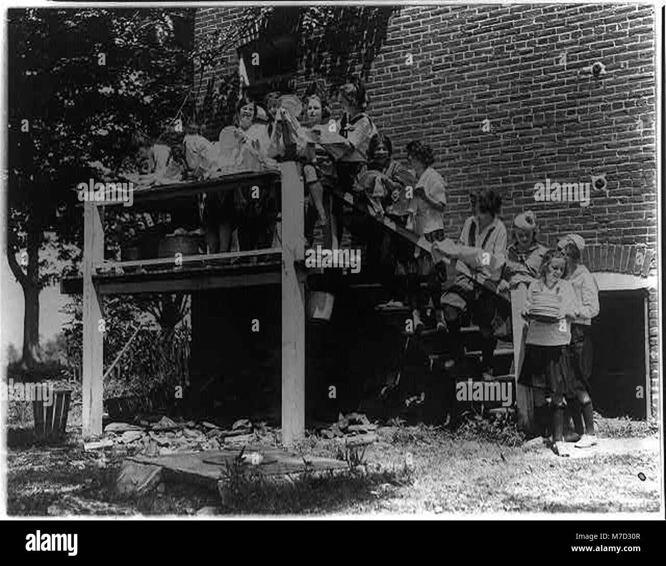 Una fotografia di ragazze di Washington, D.C., in un campo Y.W.C.A. vicino a Winona, Maryland, che le mostrano impegnate in faccende domestiche come lavare e asciugare piatti, riflettendo le attività giovanili dei primi anni del XX secolo. Foto Stock