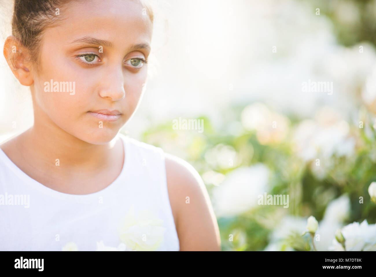 Bella ragazza in piedi in giardino guardando lontano Foto Stock