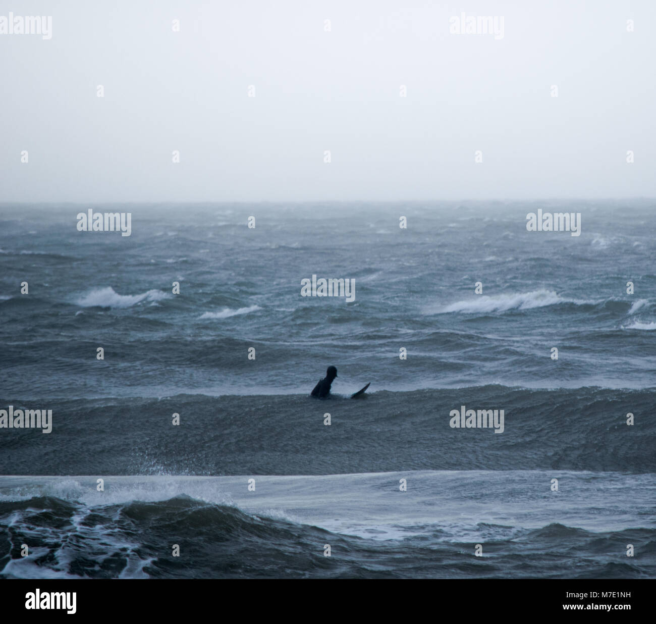 Surfer attende nella nebbia al largo a Bournemouth Pier Foto Stock