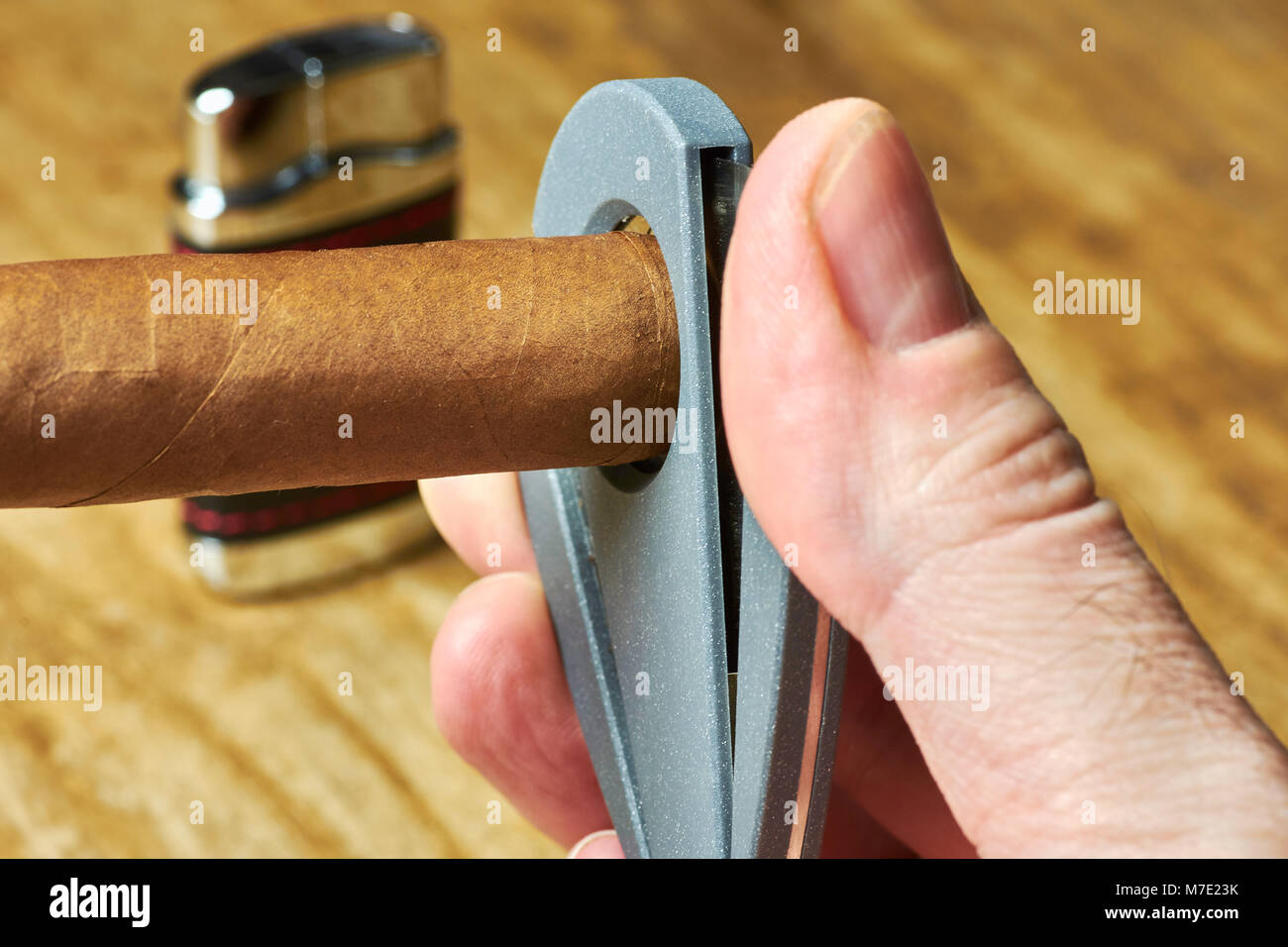 Un sigaro cubano con un maschio di mano che tiene una taglierina e un accendino sfocata in background Foto Stock