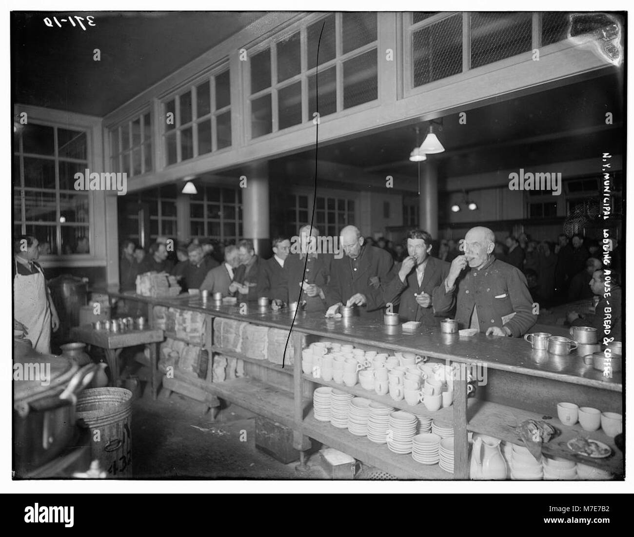 Un'immagine storica della New York Municipal Lodging House, che mostra il semplice pasto a base di pane e caffè servito agli ospiti, evidenziando i primi servizi sociali della città per i senzatetto. Foto Stock