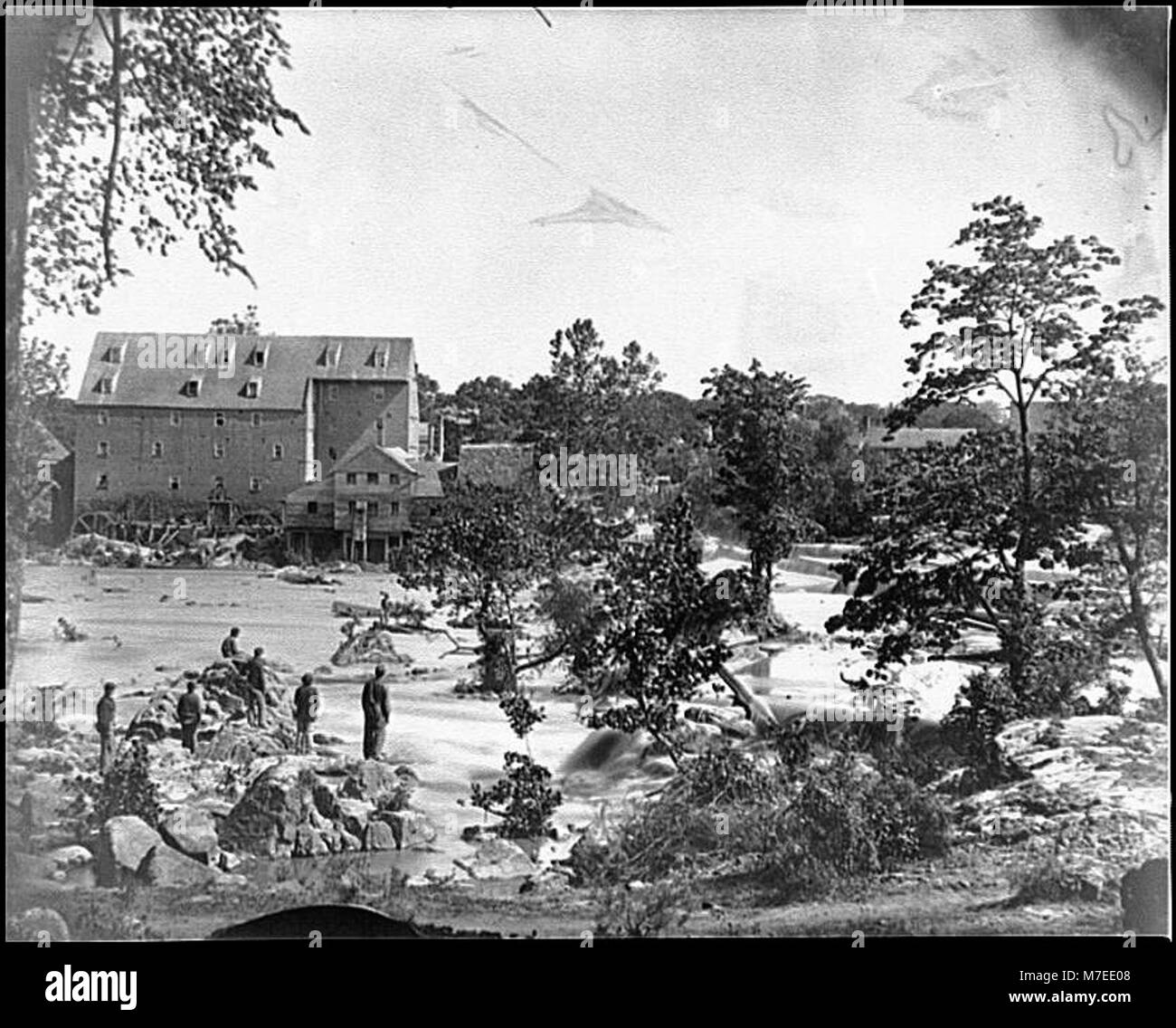 Una scena dall'area di Petersburg, Virginia, che mostra Johnson's Mill vicino a Campbell's Bridge sul fiume Appomattox, con soldati in piedi su rocce nel torrente. Questa immagine mette in evidenza la storia della guerra civile della regione. Foto Stock Una scena dall'area di Petersburg, Virginia, che mostra Johnson's Mill vicino a Campbell's Bridge sul fiume Appomattox, con soldati in piedi su rocce nel torrente. Questa immagine mette in evidenza la storia della guerra civile della regione. Foto Stock