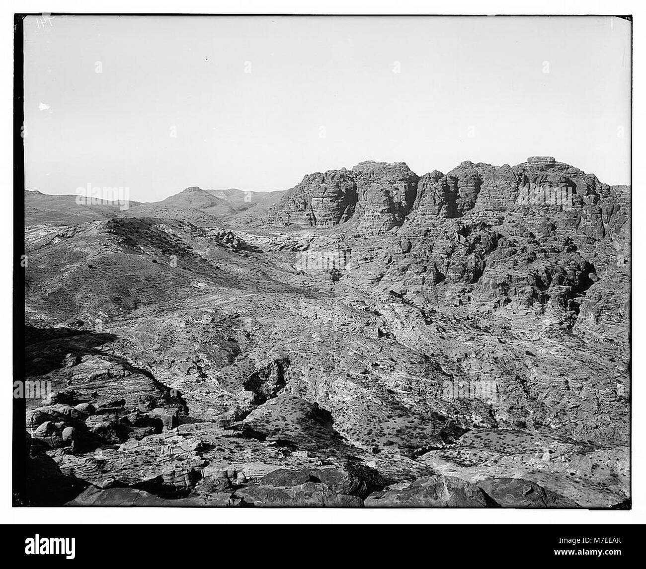 Questa immagine panoramica mostra il suggestivo paesaggio montuoso di Petra, Giordania, diviso in tre sezioni, che mostra la sua antica architettura scavata nella roccia e il terreno accidentato. Foto Stock
