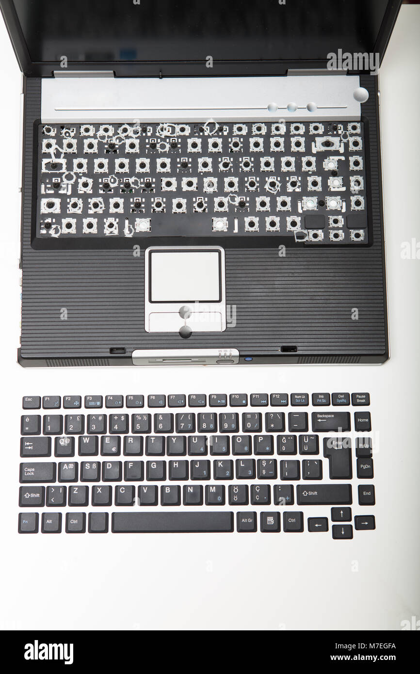 Aprire il portatile con il tasto alfanumerico rivestimenti dalla tastiera rimossi e posti in ordine su una superficie bianca nella parte anteriore del computer visto dal Foto Stock