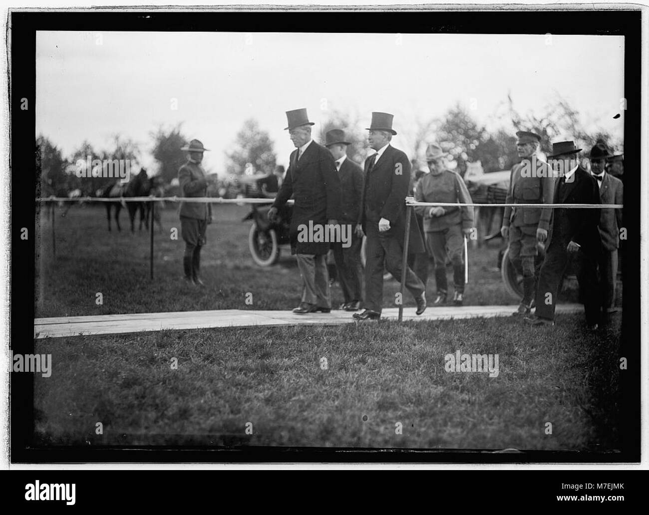 Una fotografia del presidente Woodrow Wilson e del segretario alla guerra Newton D. Baker che assistono ad un'esercitazione militare a Fort Myer, Virginia, a beneficio di un ente di beneficenza locale. L'evento mette in evidenza il loro coinvolgimento nel servizio pubblico e nel supporto della comunità. Foto Stock