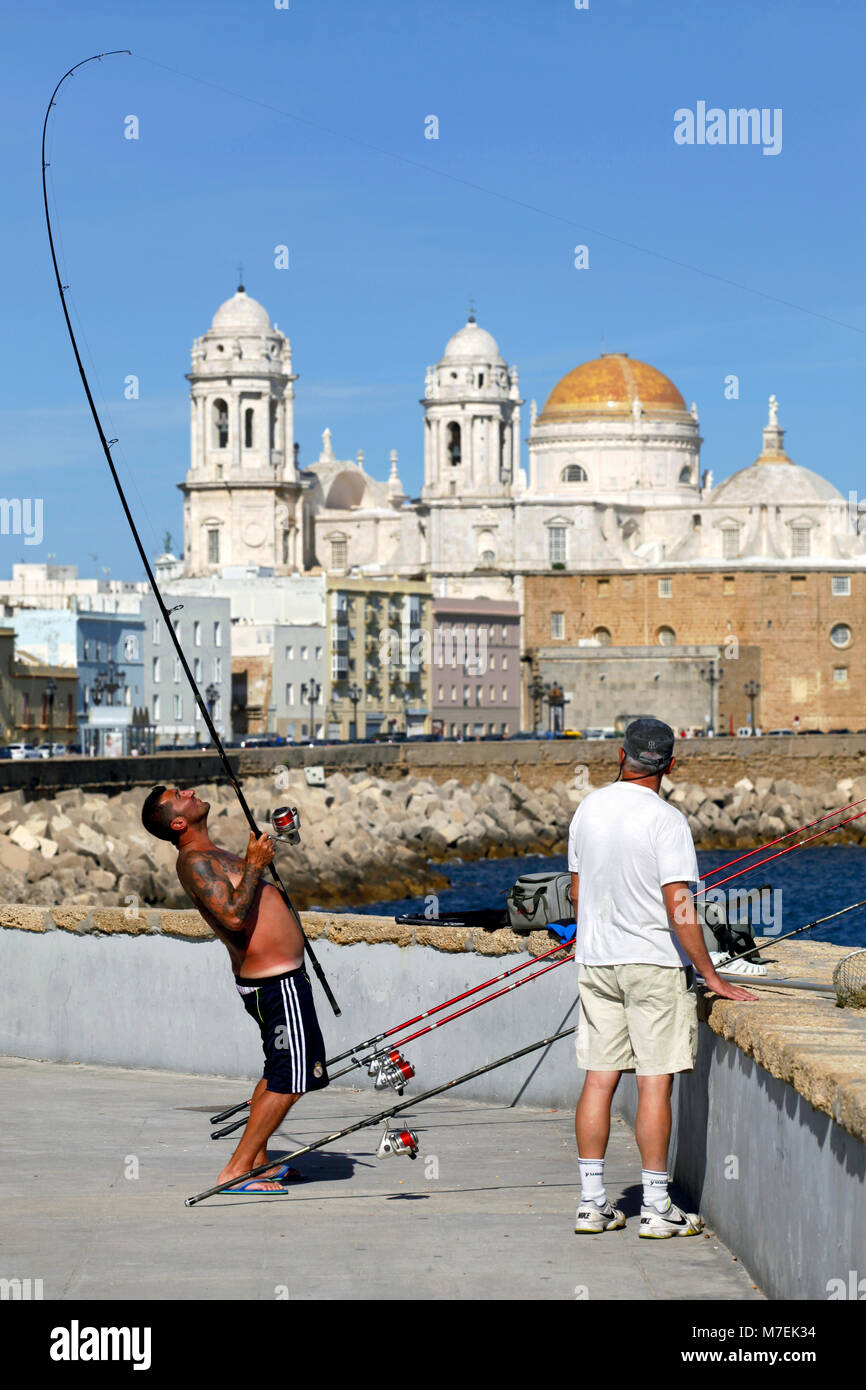 Due uomini la pesca non lontano da Catedral de la Santa Cruz sobre las Aguas de Cádiz / Cádiz cattedrale, Cadice, Andalusia, Spagna Foto Stock