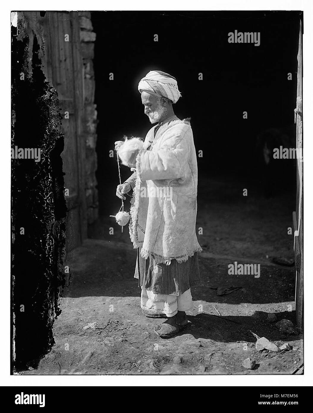 Questa immagine mostra un contadino di Ramallah, in Palestina, che filtra lana, illustrando l'artigianato tradizionale e la vita rurale della regione. Foto Stock