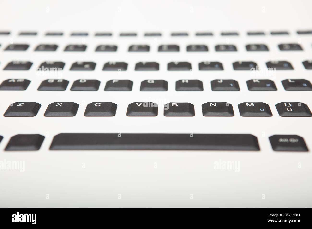 Basso angolo vista di una alfanumerica QWERTY computer tastiera con tasti neri su gradiente di argento al bianco con il fuoco selettivo per la parte di chiavi centrale Foto Stock