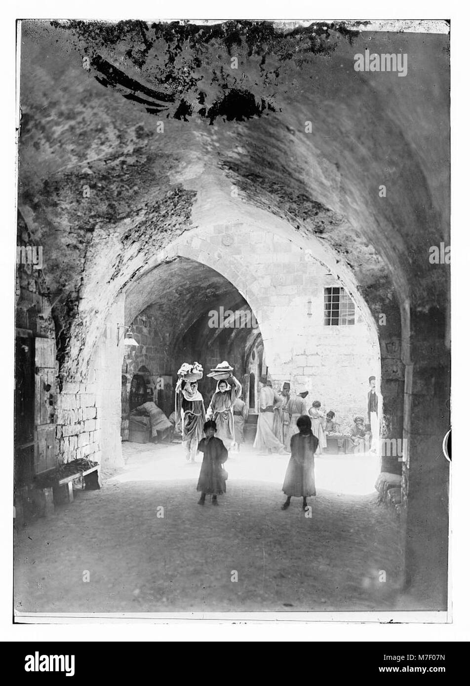 Una scena di strada di una città storica, probabilmente Gerusalemme, che mostra la tipica vita urbana e l'architettura dell'epoca. L'immagine riflette le attività quotidiane e il layout della città. Foto Stock