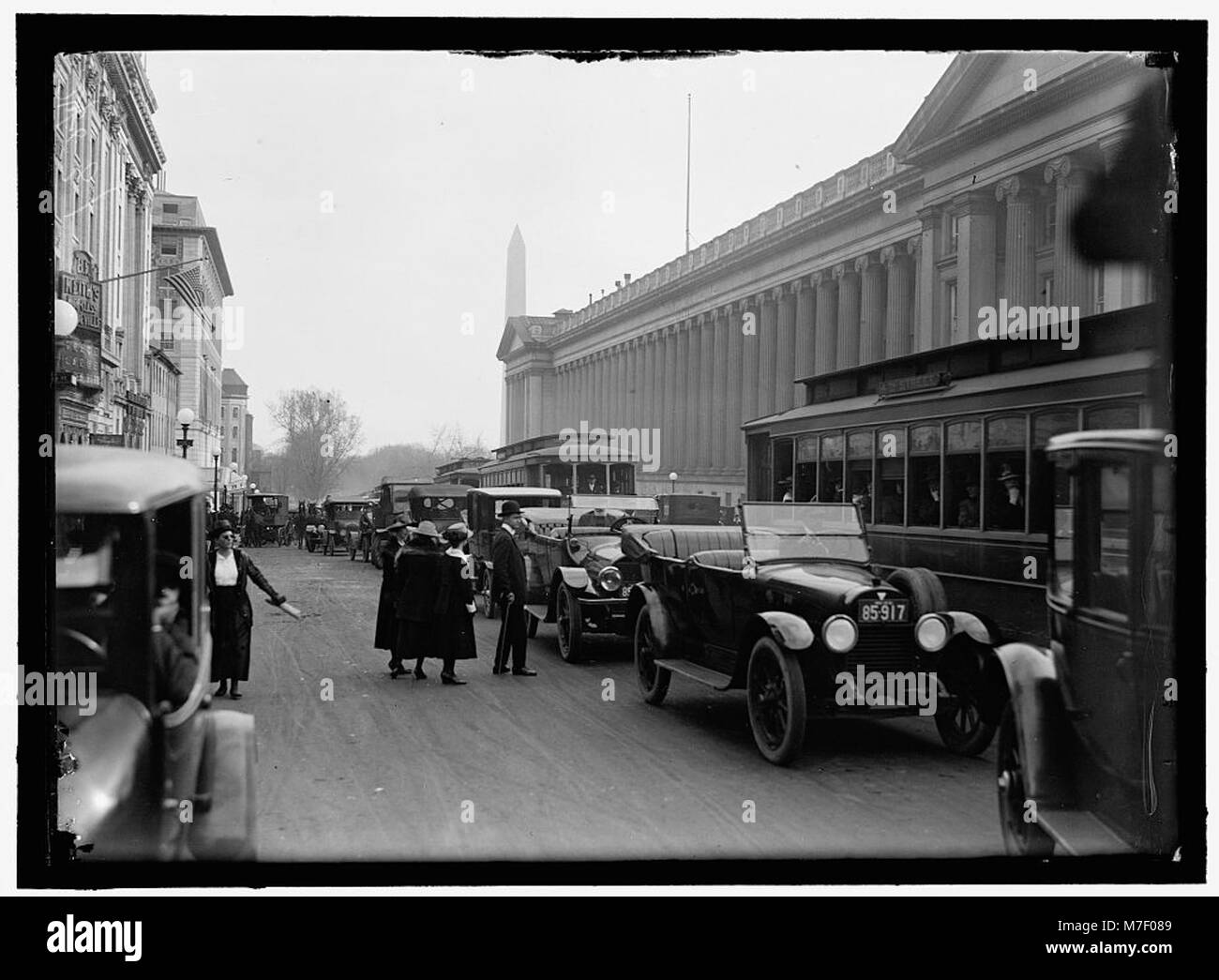 Una scena di strada che mostra il Monumento a Washington sullo sfondo, catturando l'ambiente urbano e il punto di riferimento storico. L'immagine riflette il posto del monumento all'interno del paesaggio di Washington D.C.. Foto Stock