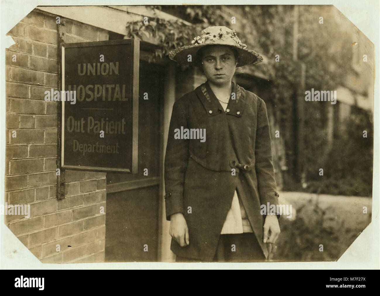 Questa fotografia raffigura Theresa Quinlan, una ragazza di 14 anni che lavora in una fabbrica di ferro, tagliando le fasce da uno spooler dopo due settimane di apprendimento del mestiere, mostrando l'ambiente di lavoro industriale dei primi anni del XX secolo. Foto Stock