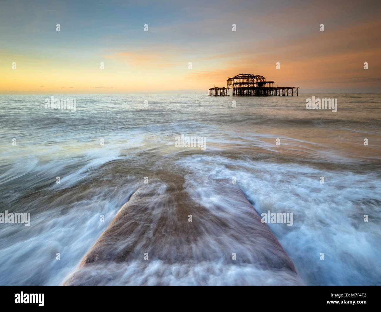 Acqua correndo su un molo di pietra presso il molo vecchio, Brighton. Foto Stock