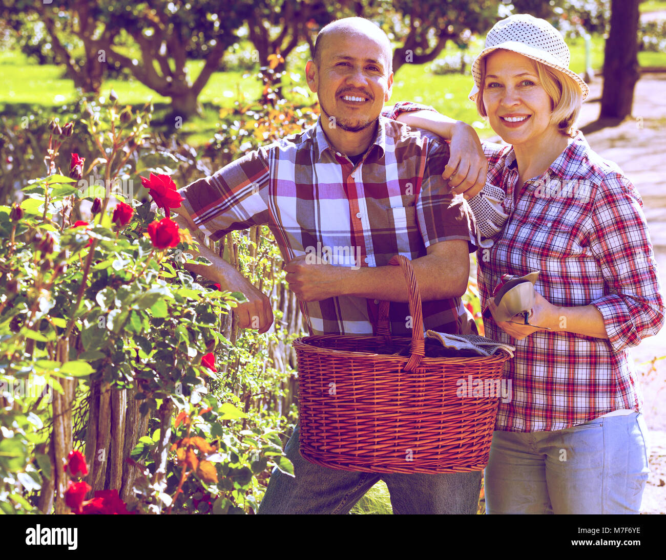 Affascinante coppia coniugi cerca dopo i fiori nel giardino in una giornata di sole Foto Stock