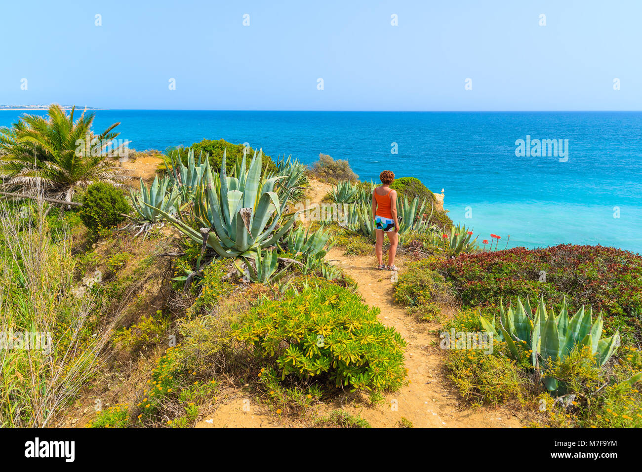 Giovane donna tourist permanente sulla scogliera vicino a Armacao de Pera comune, Algarve, PORTOGALLO Foto Stock