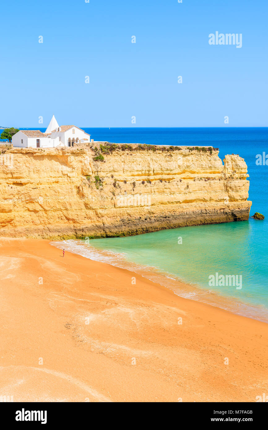 Vista della spiaggia con scogli di roccia e chiesa bianca in Armacao de Pera comune, Algarve, PORTOGALLO Foto Stock