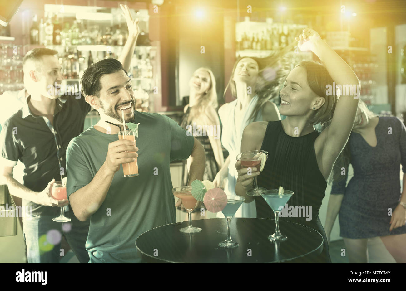 Felice maschio con femmina sono a parlare e a bere un cocktail sulla parte in club Foto Stock