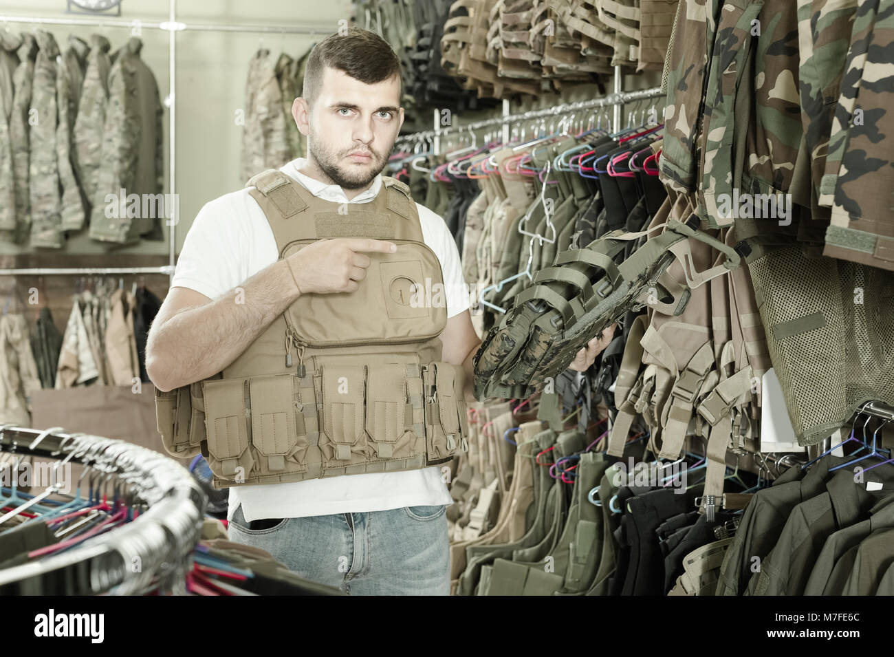 Positivo giovane ragazzo americano scegliendo flak jacket in negozio  militare Foto stock - Alamy