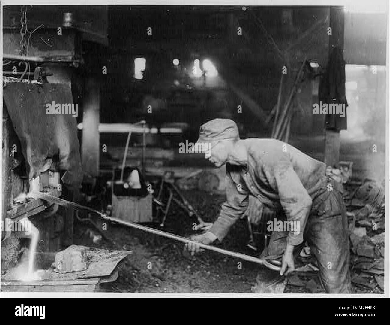 Questa fotografia mostra un operaio dell'acciaio durante il grande sciopero dell'acciaio, sottolineando la disputa sul lavoro sulla retribuzione. Il lavoratore viene mostrato durante il processo di pompaggio, modellando il ferro da trasportare al forno per un'ulteriore lavorazione. Foto Stock