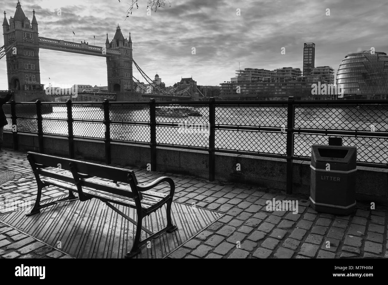 Foto in bianco e nero di una panchina nel parco rivolta verso il Tower Bridge e il Tamigi all'alba Foto Stock
